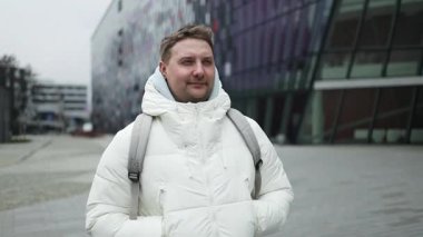 Sırt çantalı, gülümseyen beyaz sakallı bir adamın portresi. Kış şehrindeki kameraman agnist havaalanı terminaline bakıyor. Yaşam tarzı, şehir hayatı konsepti. Yüksek kalite fotoğraf