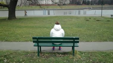 Söğüt ağacının altındaki bankta tek başına oturan genç adam suya bakıyor. Yüksek kalite fotoğraf