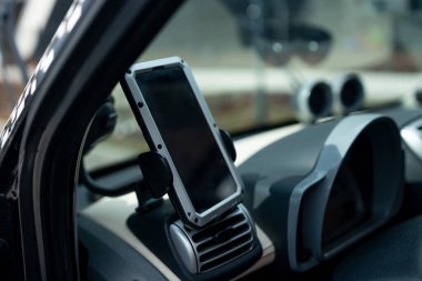 Araba gösterge panelindeki telefon tutacağına modern akıllı telefon aygıtı monte edilmiş. Model beyaz ekran izole şablonu. Araç iç kokpit manzaralı. Akıllı telefon için evrensel bağlanma tutucusunu kapat