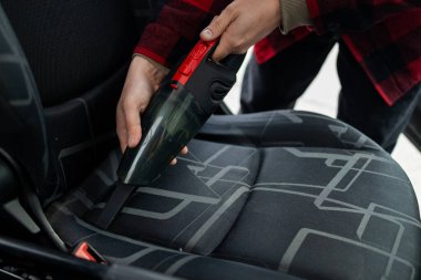 Araba süpürgesinin detayları. Kirli araba için elektrikli süpürge kullanan profesyonel kırpılmış erkek işçi. Otomobil servisi sürücü koltuğunu temizliyor, temizlik ve süpürme konsepti. Yüksek