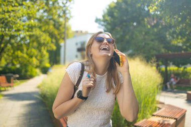Yaz parkında telefonla konuşan, kameraya bakan, 30 'lu yaşlarda serbest çalışan bir öğrencinin portresi. Kentsel yaşam tarzı kavramı. Yüksek kalite fotoğraf