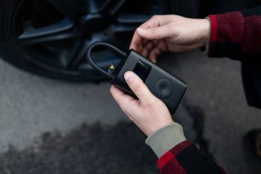 Adam sürücü elinde araç lastikleri şişiriyor, hava basıncını kontrol etmek ve benzin istasyonunda tekerleği doldurmak için lastik kapakçığı kapağını çıkarıyor. Kişisel hizmet, bakım ve güvenlik. Yüksek kalite