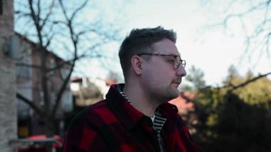 Yakışıklı adam kameraya bakıyor. Yakından pozitif adam kameraya gülümsüyor. Yeşil parktaki kamera önünde poz veren erkek modelin portresi. Neşeli bir adam yüzü ve dışarıda olumlu duygular var. Yüksek kalite FullHD