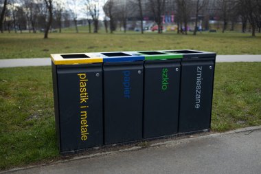 Parkta geri dönüşüm için dört ayrı çöp kutusu var. Her biri plastik, kağıt, metal ve atık olarak etiketlenmiş. Renkli kutular atık ayıklama ve geri dönüşüm için çevresel çabaları destekliyor