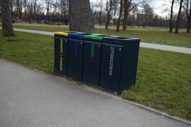 Parkta geri dönüşüm için dört ayrı çöp kutusu var. Her biri plastik, kağıt, metal ve atık olarak etiketlenmiş. Renkli kutular atık ayıklama ve geri dönüşüm için çevresel çabaları destekliyor