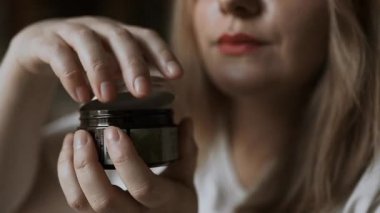 Bornozlu güzel bir kadın sabah rutininde yüz kremi sürmüş ve aroma kokluyor. Deri bakımı konsepti. Kıvırcık saçlı, mükemmel ciltli, duştan sonra nemlendirici kullanan genç bir kadın. Yüksek