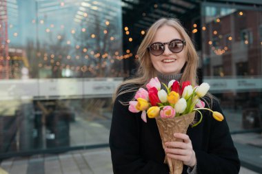Güzel, mutlu, beyaz bir kadın. Gözleri kapalı laleler kokluyor. Yüksek kalite 