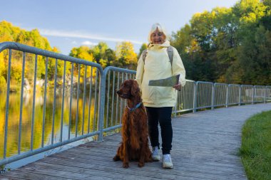 Sonbahar doğasında seyahat haritası ve köpeği olan yaşlı bir kadın. Yüksek kalite fotoğraf