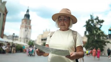  Kadın, Polonya 'nın başkenti Krakow' da muhteşem bir mimari ve arka planda güzel bir gökyüzü olan bir haritayı dikkatle inceliyor. O bir turist olarak şehri keşfediyor..