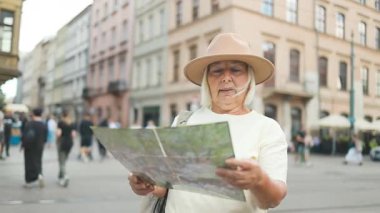 Kadın, Polonya 'nın başkenti Krakow' da muhteşem bir mimari ve arka planda güzel bir gökyüzü olan bir haritayı dikkatle inceliyor. O bir turist olarak şehri keşfediyor..