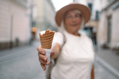 Keyifli bir günde elinde dondurma külahıyla gezen neşeli, son sınıf öğrencisi bir kadın sokakta gezinirken eğleniyor. Mükemmel bir rahatlama ve hoşgörü anı..