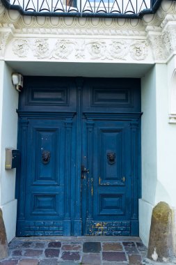 Karmaşık ahşap işçiliği ve dekoratif memeleri olan bir çift klasik mavi kapı. Kapılar, eski bir taş bina, cazibe ve tarih. Huzurlu bir şehir sokağında yakalandı.