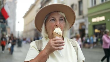 Yaşlı bir kadın şehirde dolaşırken dondurma külahı yiyor. Güneşli bir günde tatlı bir ziyafetin tadını çıkarıyor. Şapka ve rahat giysiler giyiyor..
