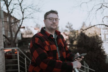 Yakışıklı adam kameraya bakıyor. Yakından pozitif adam kameraya gülümsüyor. Yeşil parktaki kamera önünde poz veren erkek modelin portresi. Neşeli bir adam yüzü ve dışarıda olumlu duygular var. Yüksek kalite FullHD