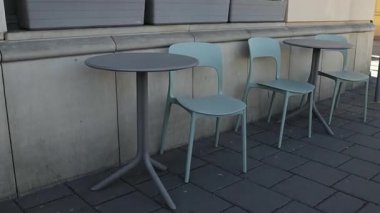 Şehir caddesi boyunca birkaç modern masa ve sandalyeyle kurulmuş minimalist bir açık kafe. Masalar sıraya dizildi, rahat ve davetkar bir açık hava alanı sağlandı.