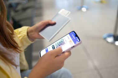 Elinde pasaport ve uçuş kartı tutarken biletini kontrol eden siyahi iş kadınının elini kapat. Afrikalı Amerikalı bir kadın cep telefonundan online seyahat biletini kontrol ediyor. Yüksek