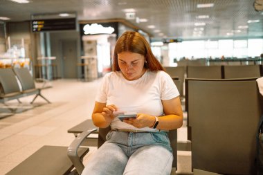 Kadınlar havaalanında uçağa binmek için beklerken akıllı telefon ve pasaport kullanırlar. Yüksek kalite fotoğraf