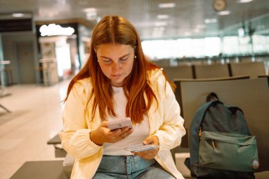 İş kadınının elinde pasaport ve uçuş kartı tutarken telefon biletini kontrol etmesini kapat. Kadın cep telefonundan internet üzerinden seyahat biletini kontrol ediyor. Yüksek kalite fotoğraf