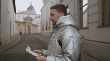 Seyrüsefer haritasını kullanarak eski şehir sokağı Krakow 'da bir yol arayan turist gezgini. Beyaz, sakallı bir erkek, şehrin arka sokaklarından geçiyor..