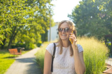 Yaz parkında telefonla konuşan, kameraya bakan, 30 'lu yaşlarda serbest çalışan bir öğrencinin portresi. Kentsel yaşam tarzı kavramı. Yüksek kalite fotoğraf