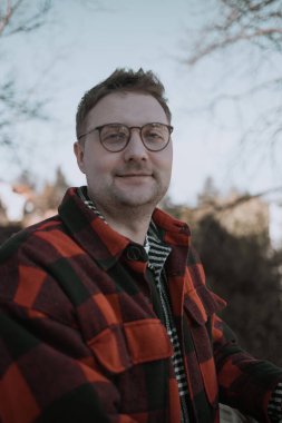 Yakışıklı adam kameraya bakıyor. Yakından pozitif adam kameraya gülümsüyor. Yeşil parktaki kamera önünde poz veren erkek modelin portresi. Neşeli bir adam yüzü ve dışarıda olumlu duygular var. Yüksek kalite FullHD