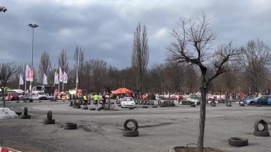 Polonya 'nın Krakow kentindeki açık bir otoparkta canlı bir araba etkinliği. Sürüklenen arabalar, izleyiciler, bayraklar ve güvenlik bariyerleri. Sahne, bir motor sporunun heyecanını ve enerjisini yakalıyor..