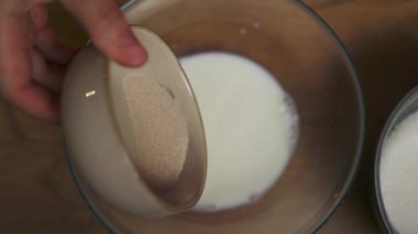 Bir kase sıcak süte kuru maya ekleme görüntüsü. Ekmek ya da kek pişirmede klasik bir ilk adım. Mutfak blogları, özel dersler veya zanaatkar pişirme içeriği için ideal
