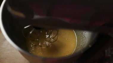 Tahta bir yüzeyde metal bir kasede yumurta ve şeker çırpan bir elektrikli standın yakın çekimi. Ev yapımı konusunda ayrıntılı bir adım, yemek dersleri, tarif içeriği ve yemek blogları için ideal.