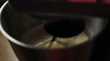 Elektrikli mikser hamuru ya da kremayı paslanmaz çelik bir kaseye yakın plan. Pişirme hazırlığında klasik bir adım, yemek dersleri, yemek tarifleri, yemek blogları ve yavaş yaşam içeriği için ideal.