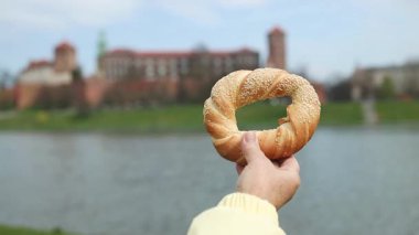 Avrupa, Krakow 'daki eski şehir merkezi manzarasında geleneksel Polonya yemeği olan simit obwarzanek' i tutan turist kadın.. 