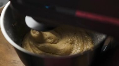 Elektrikli mikser hamuru ya da kremayı paslanmaz çelik bir kaseye yakın plan. Pişirme hazırlığında klasik bir adım, yemek dersleri, yemek tarifleri, yemek blogları ve yavaş yaşam içeriği için ideal.