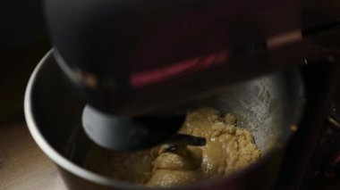 Elektrikli mikser hamuru ya da kremayı paslanmaz çelik bir kaseye yakın plan. Pişirme hazırlığında klasik bir adım, yemek dersleri, yemek tarifleri, yemek blogları ve yavaş yaşam içeriği için ideal.