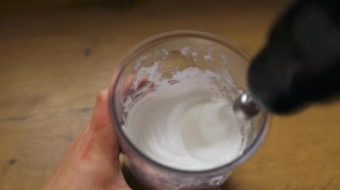 Bardakta krema ya da krema kırbaçlayan el bilgisayarı görüntüsü. Tatlı ya da pasta dekorasyonunda nefis bir adım, yemek blogları, tatil pişirme ve yemek tarifi videoları için mükemmel..
