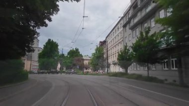Krakow, Polonya 'daki yeşil şehir caddesinde tramvay rayları. Krakow 'da yapraklı bir caddede, tramvay rayları boyunca ilerleyen yüksek kaliteli 4K' lık bir görüntü. Konut binaları, ağaçlar ve şehir manzarası.