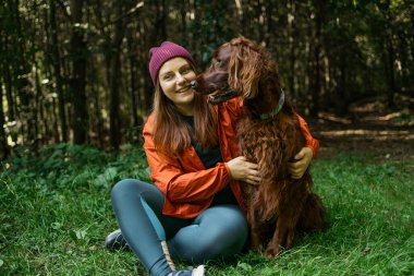 Ormanda köpekleriyle oynarken gülümseyen bir kadın. Sevgiyi, neşeli havayı ve doğada rahatlatıcı zamanı gösterir..