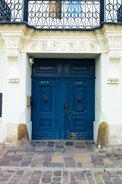 Karmaşık ahşap işçiliği ve dekoratif memeleri olan bir çift klasik mavi kapı. Kapılar, eski bir taş bina, cazibe ve tarih. Huzurlu bir şehir sokağında yakalandı.