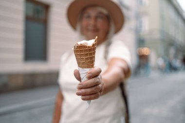 Keyifli bir günde elinde dondurma külahıyla gezen neşeli, son sınıf öğrencisi bir kadın sokakta gezinirken eğleniyor. Mükemmel bir rahatlama ve hoşgörü anı..