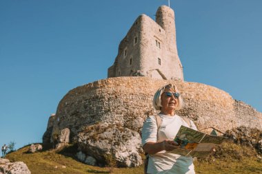 Güneş gözlüklü, yaşlı ve mutlu yalnız gezgin kadın. Yazın Polonya 'nın Mirow Kalesi yakınlarında eğleniyor. Yüksek kalite fotoğraf