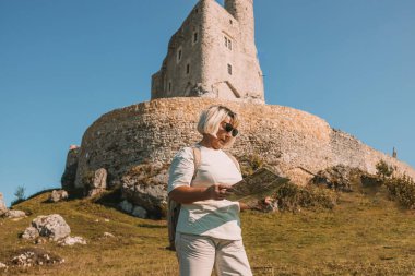 Güneş gözlüklü, yaşlı ve mutlu yalnız gezgin kadın. Yazın Polonya 'nın Mirow Kalesi yakınlarında eğleniyor. Yüksek kalite fotoğraf