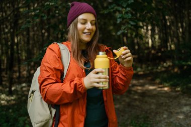 Dağın tepesinde güzel 30 'lu yaşlarda bir kadın manzarayı seyrediyor. Kadın gezgin dağcı elinde su şişesiyle güzel manzaraya bakıyor. Macera, seyahat. Yüksek kalite fotoğraf
