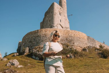 Güneş gözlüklü, yaşlı ve mutlu yalnız gezgin kadın. Yazın Polonya 'nın Mirow Kalesi yakınlarında eğleniyor. Yüksek kalite fotoğraf