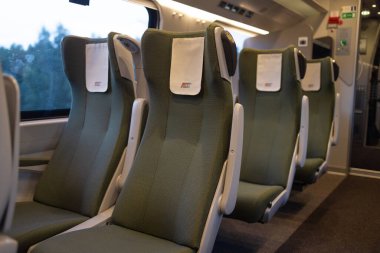 Gdansk, Polonya - 3 Eylül 2023: Temiz, boş yeşil koltukları ve başlıkları olan modern bir Polonya treninin içi. Seyahat içeriği ve toplu taşımacılık için sessiz ve düzenli bir demiryolu alanı