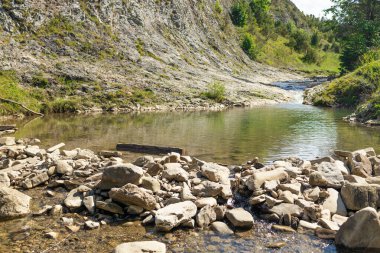 Berrak sularla çevrili, yeşil ve dik yamaçlarla çevrili kayalık bir vadide dalgalanan sakin bir dağ deresi. Dokunulmamış doğanın saf güzelliğini yakalar, sükunet ve ekoloji temaları için mükemmeldir.