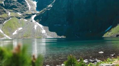 Polonya 'nın Tatra Dağları' ndaki temiz bir alp gölünün çarpıcı manzarası. Kayalık tepeler ve eriyen kar parçalarıyla çevrili bu barışçıl manzara doğa, seyahat ve yürüyüş görselleri için mükemmeldir..