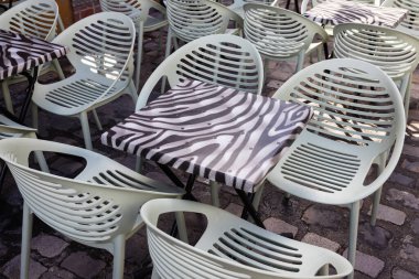 Modern sandalyeler ve kaldırımdaki açık hava restoranının masaları.