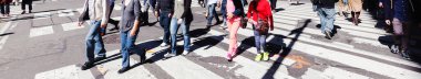 panoramic picture of crowds of people crossing a city street