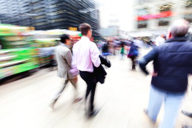 picture with camera made motion blur effect of business men walking on a busy city street