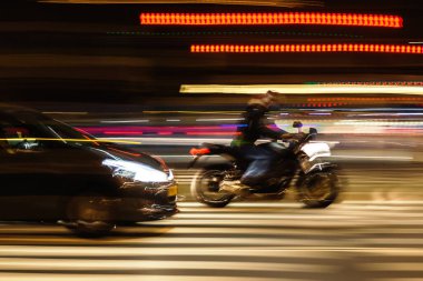 abstract blurred image of a car and a motorcycle on a city street at night