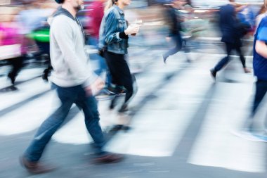 picture with camera made motion blur effect of a crowd of people crossing a busy street in the city