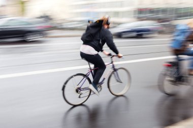 picture with motion blur effect of a man on a bicycle on the move on a rainy street in the city